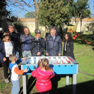Nella foto il biliardino nell'area verde, dietro gli inervenuti alla consegna, in primo piano di spalle e pixellati due bambini