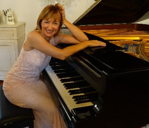 Foto dell'artista seduta di traverso (in posa) al pianoforte a coda