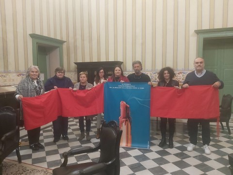Nella foto i partecipanti (nominativi nel comunicato) sorreggono il drappo e il manifesto