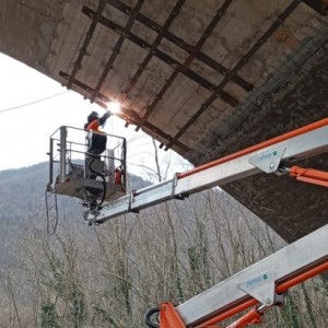 Nella foto piattaforma elevatrice con operaio al lavoro sotto il ponte