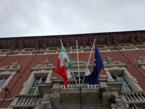 Foto di particolare della facciata del Palazo Duclae con le bandiere a mezz'asta